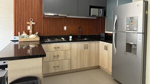 A modern kitchen with wooden cabinets, a stainless steel refrigerator, and a black countertop. - 5 minutes from the beach/private pool by Gpsrentas (Mazatlán)