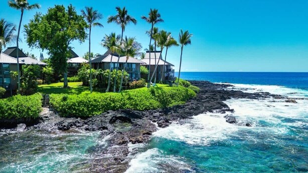 A coastal hotel with multiple buildings, lush greenery, and a view of the ocean. - Oceanfront Luxury House, Pool & AC, Near Magic Sands (Kailua-Kona)
