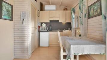 A compact kitchen with wooden cabinets, a small refrigerator, a microwave, and a sink.
