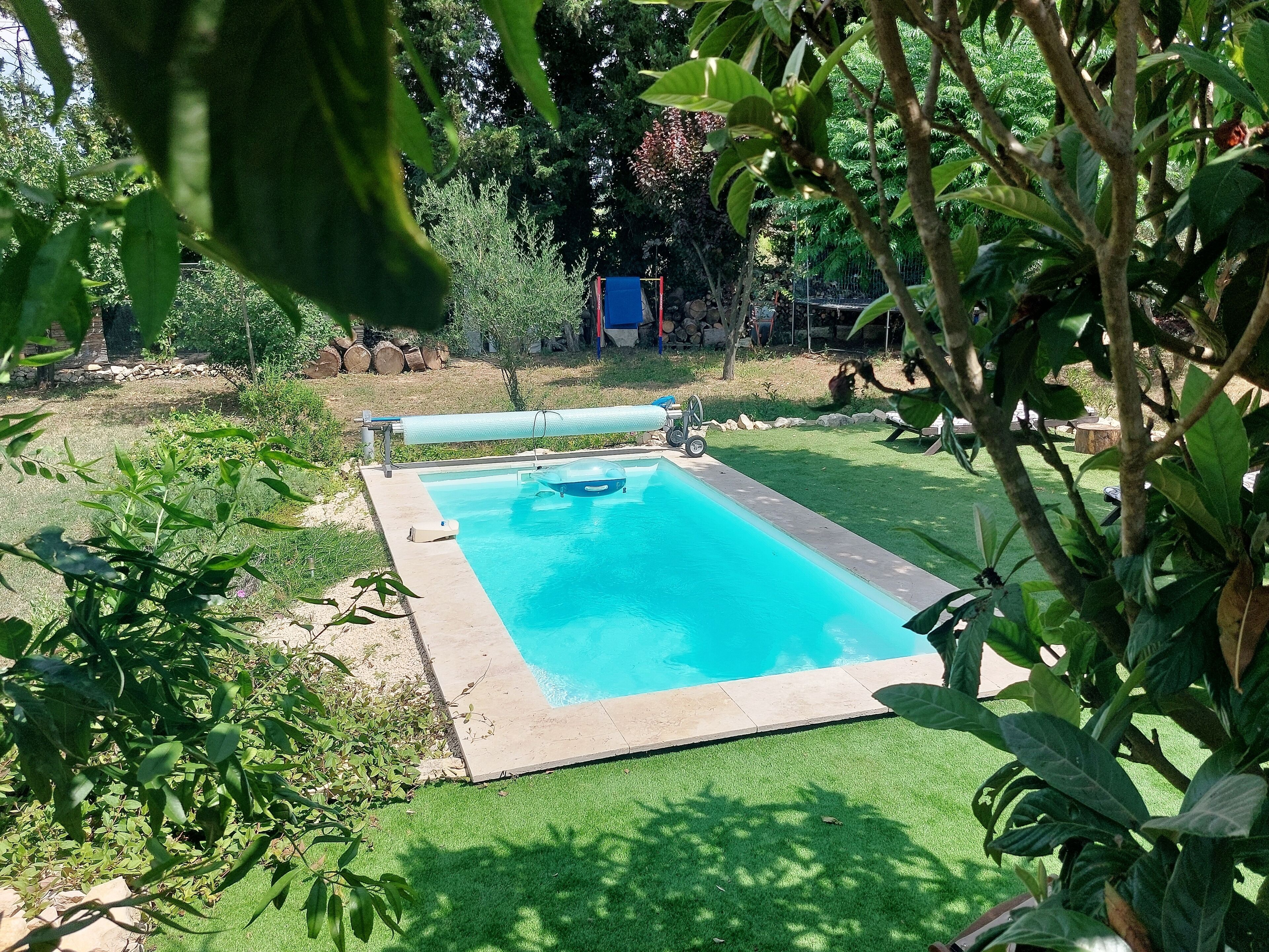 Una piscina rettangolare con interno blu, circondata da un solarium in cemento e una porzione di erba sintetica.