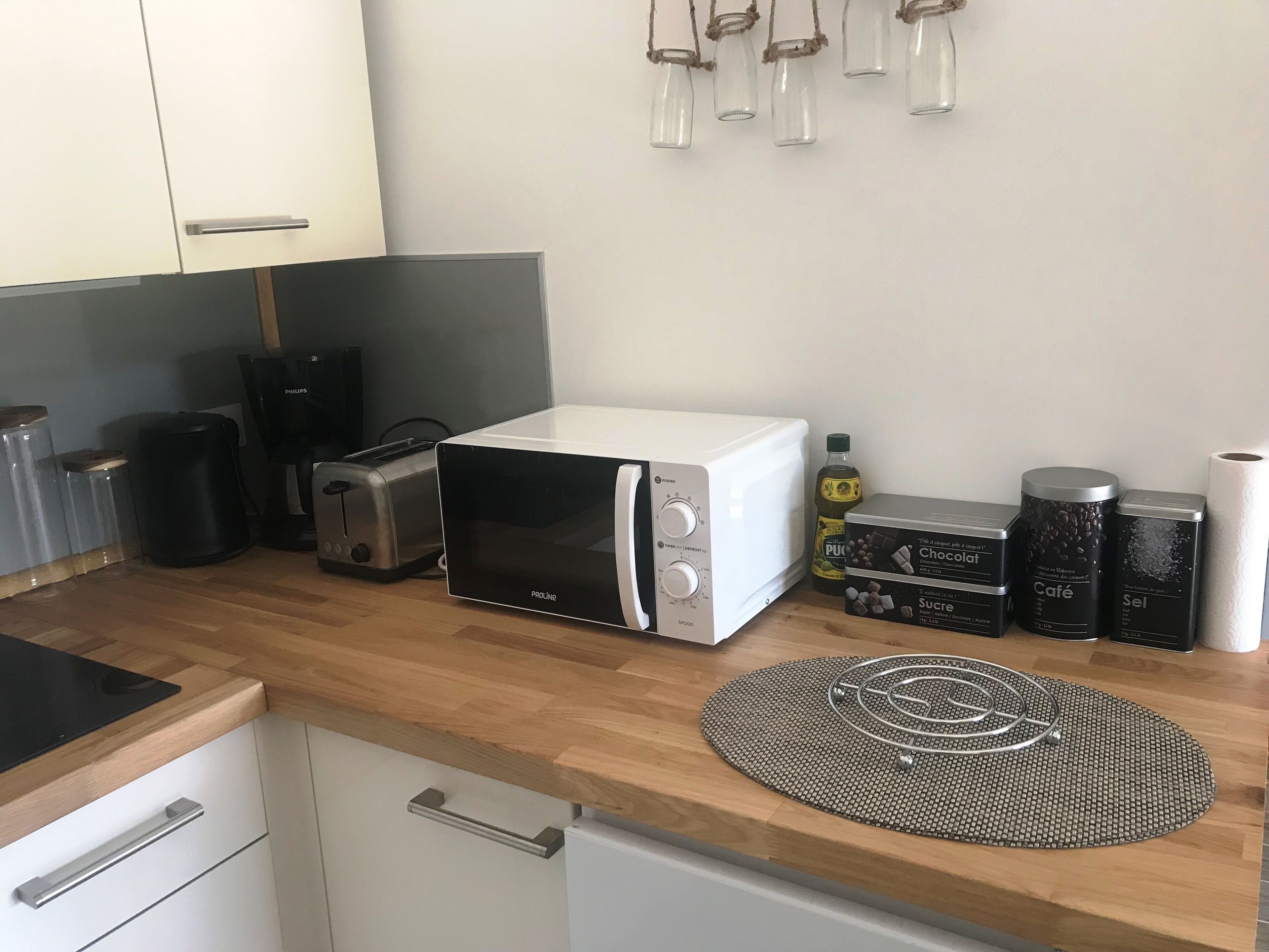 A kitchen with a microwave, toaster, and coffee maker. There are also containers on the counter.