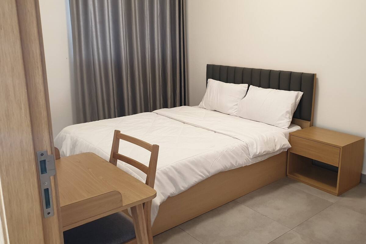 A single bed with a wooden headboard, a bedside table, and a chair.