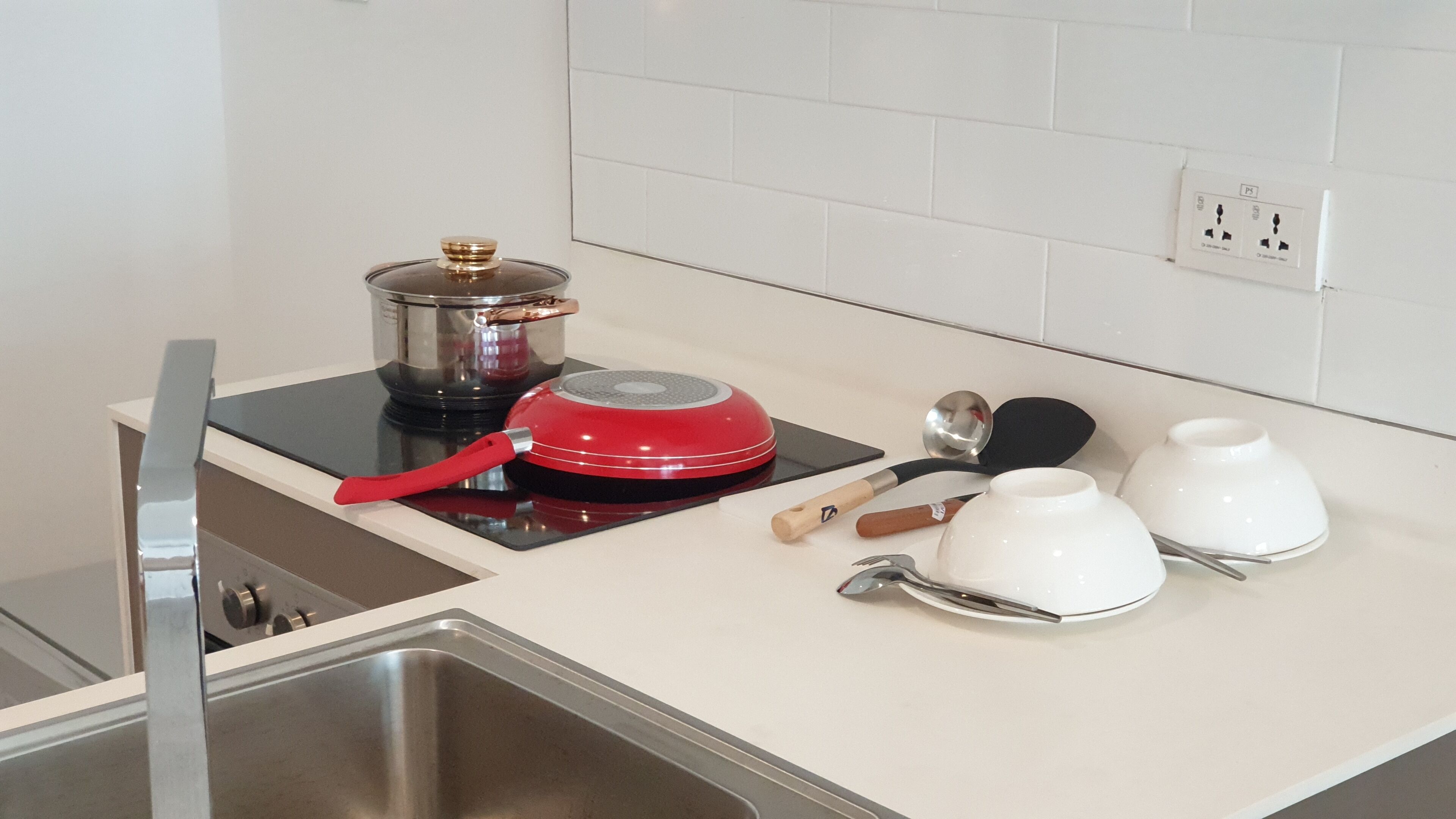 A kitchen with a stove, pots, and white cups on the counter.
