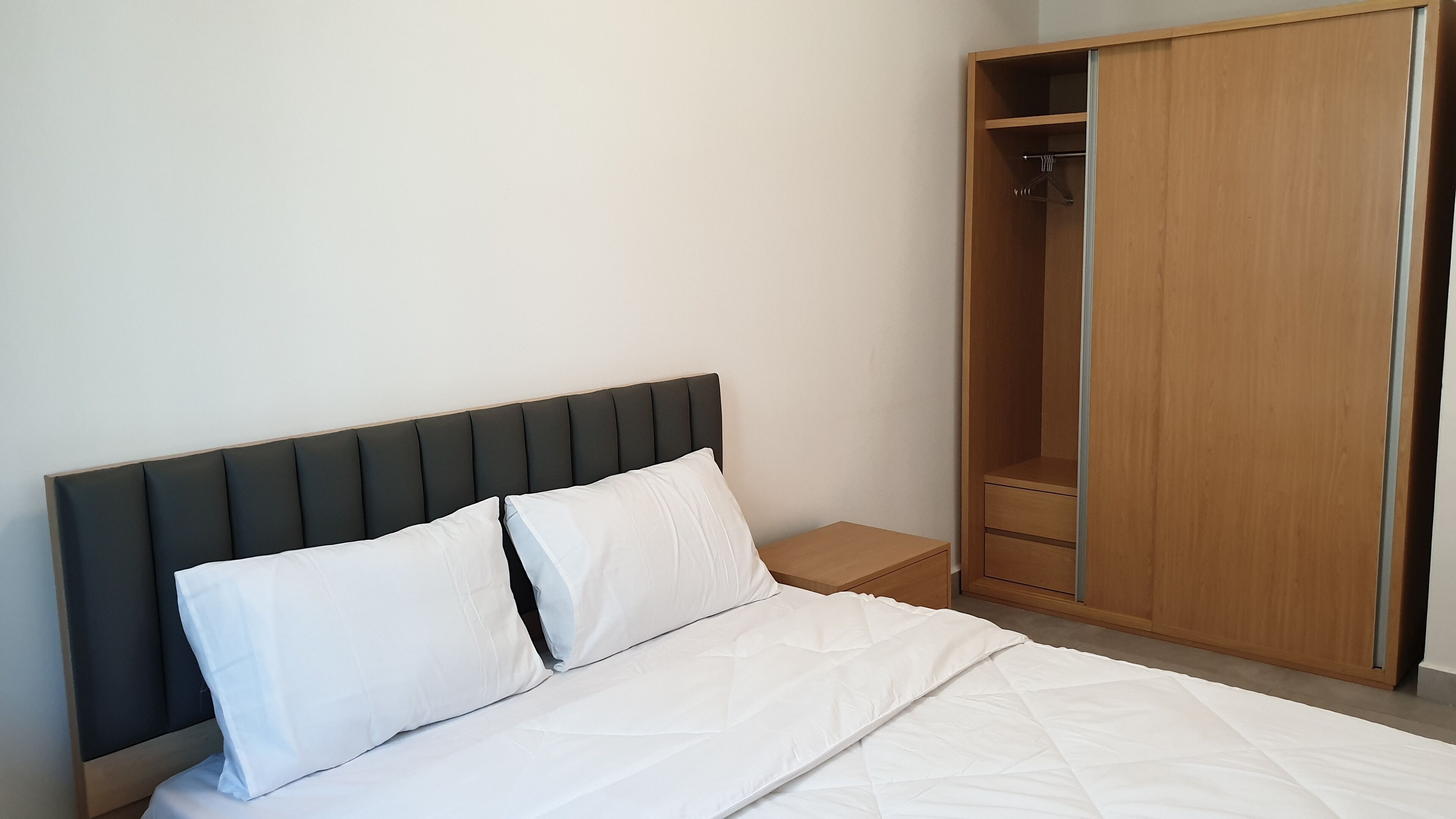 Une chambre à coucher avec un lit, une armoire en bois et une table de chevet.