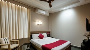 A hotel room with a bed, a chair, a desk, a ceiling fan, and a wall-mounted air conditioner. - Naadi stayinn New Busstand Thanjavur (Thanjavur)