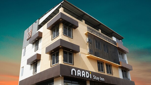 A multi-story hotel with a modern design, featuring balconies and large windows. - Naadi stayinn New Busstand Thanjavur (Thanjavur)