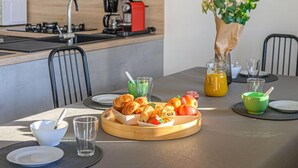 Eine moderne Küche mit einer zentralen Kochinsel, einem Esstisch mit Frühstücksgebäck und einer Kaffeemaschine.