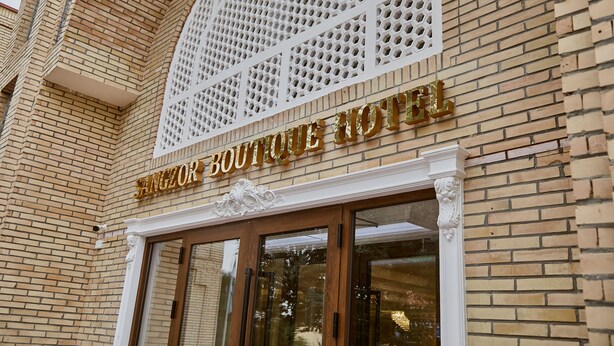 A boutique hotel entrance with a brick facade and a sign above the doors. - Sangzor Boutique Hotel (Samarkand)