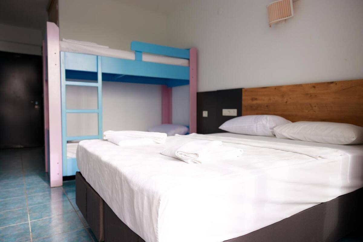 A bunk bed with a wooden headboard, a white mattress, and a blue and pink frame.