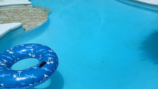 Una piscina con un flotador azul hinchable y un juguete azul.