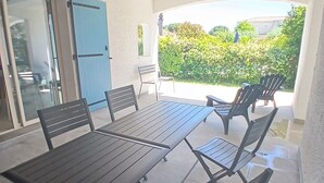 Un patio al aire libre con una mesa y sillas, una puerta azul y vistas a follaje.