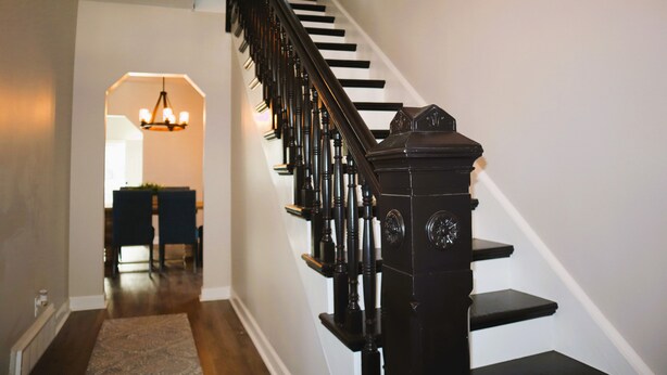 Eine Treppe mit schwarzen Geländern und einem Chandelier im Hintergrund.