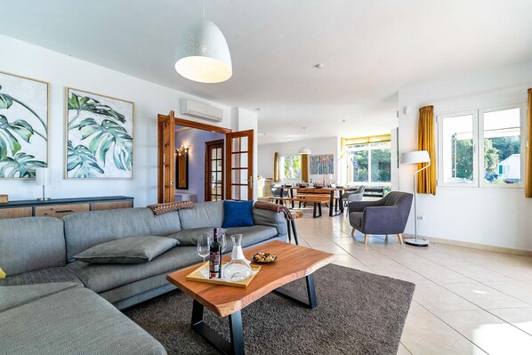 A modern living room with a grey sectional sofa, a wooden coffee table, and a dining area with a table and chairs. - Exclusive Villa With Private Pool & Views, Mijas (Mijas)