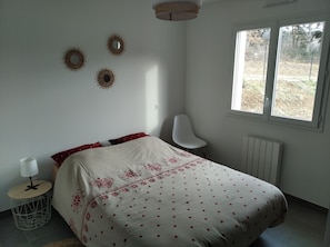 Une chambre à coucher avec un lit, une chaise, une fenêtre et des éléments décoratifs sur les murs.
