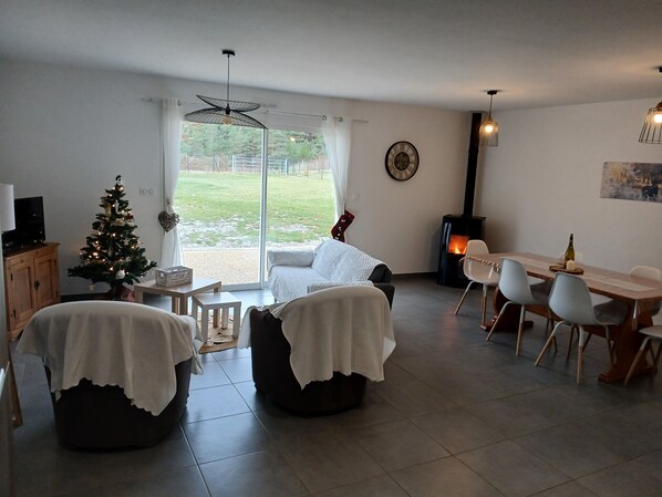 Un salon chaleureux avec une cheminée, un coin repas et un sapin de Noël.