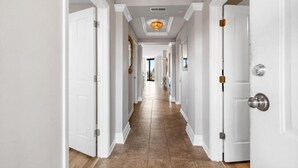 A hallway with white doors, a tiled floor, and a ceiling light fixture. - Captains Quarters 3BR Villa Steps from the Ocean (Pawleys Island)