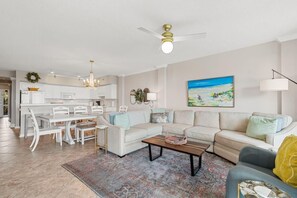 A modern living room with a sofa, coffee table, and a dining area with chairs and a table.