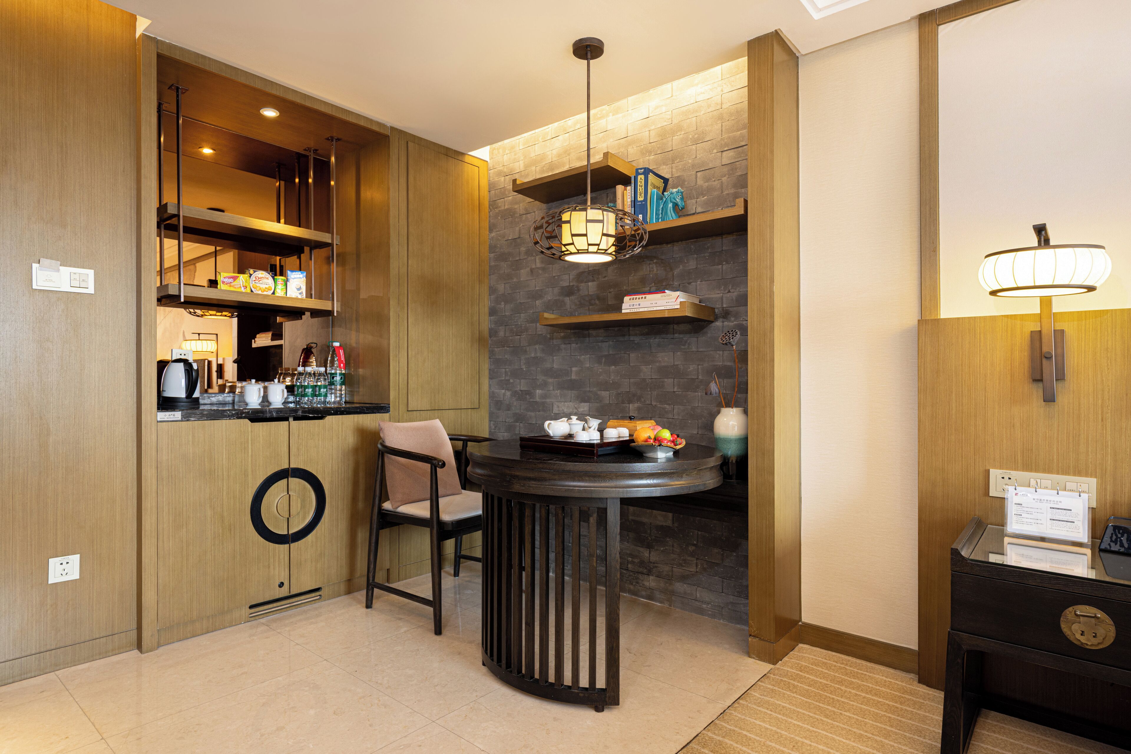 A compact kitchen with a round table, a chair, and a hanging light fixture.