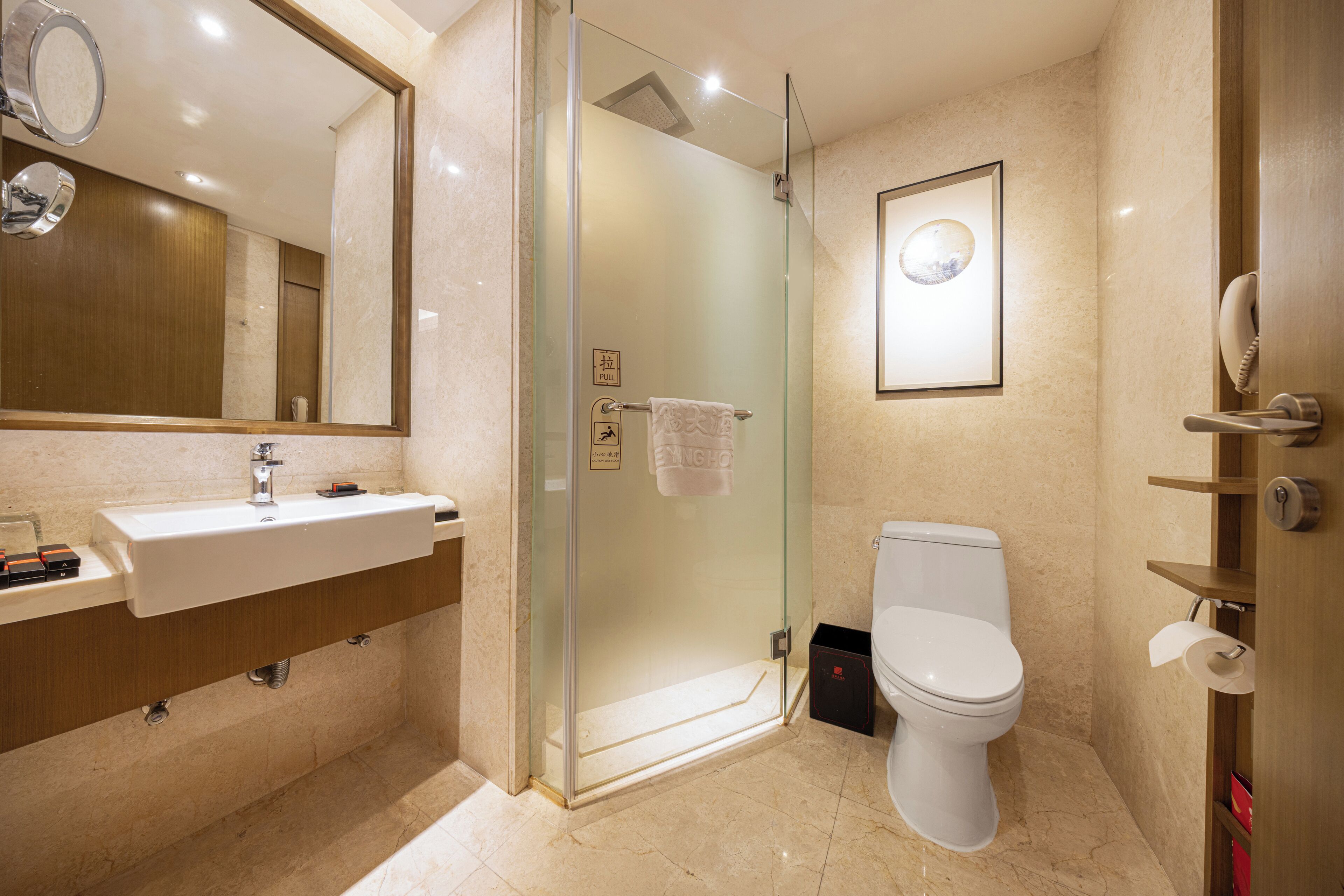 A modern bathroom with a glass-enclosed shower, a white sink, and a toilet.