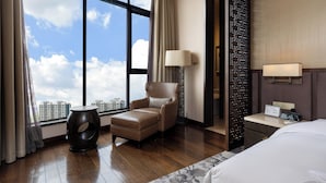 A hotel room with a large window, a leather armchair, a small ottoman, a bedside table with a lamp, and a bed. - hunanyueyangHotel (Yueyang)