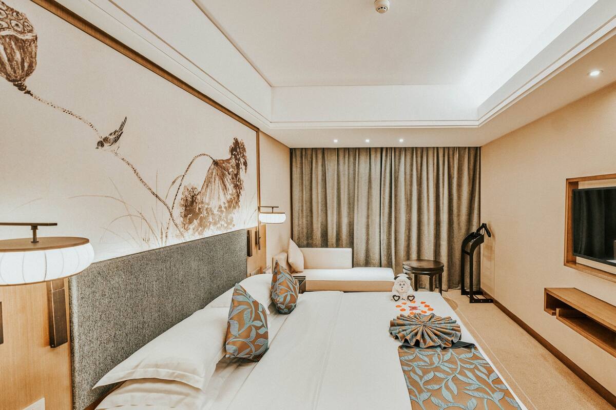 Ein modernes Hotelzimmer mit Bett, Fernseher, Schreibtisch und großem Fenster.