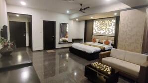 A modern hotel room with a large bed, a sofa, a coffee table, and a desk. - Hotel Restandview (Anand)