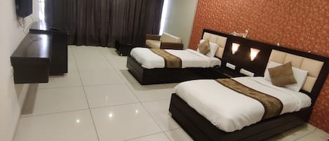 A hotel room with two beds, a TV, a ceiling fan, and a large window with curtains.