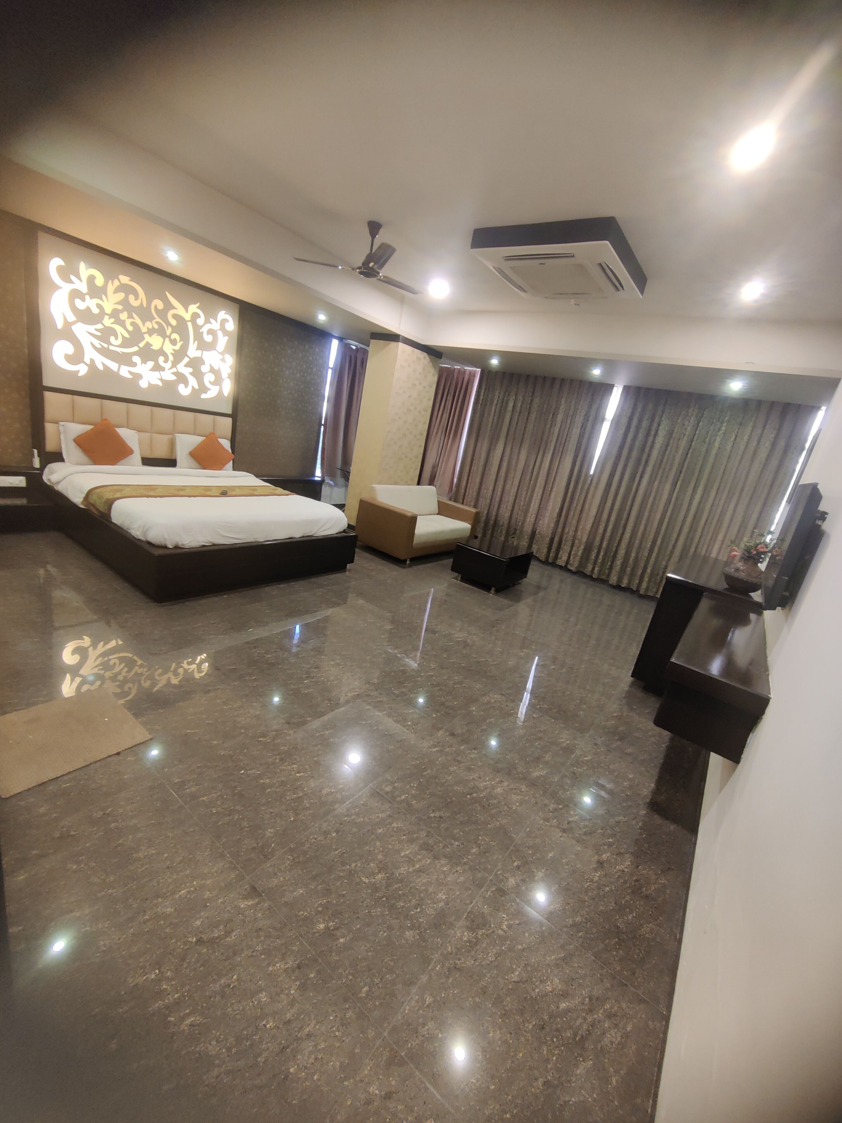 A modern hotel room with a large bed, a chair, a desk, and a TV.