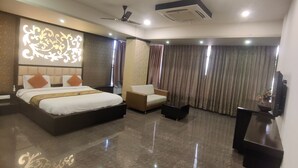 A modern hotel room with a large bed, a sofa, a desk, and a ceiling fan. - Hotel Restandview (Anand)