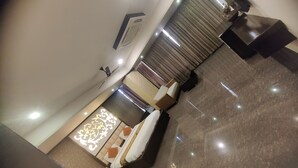 A hotel room with a bed, a desk, a chair, a ceiling fan, and a window with curtains. - Hotel Restandview (Anand)