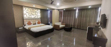 Quarto de hotel moderno com uma cama grande, um sofá, uma mesa de centro e uma televisão de tela plana.