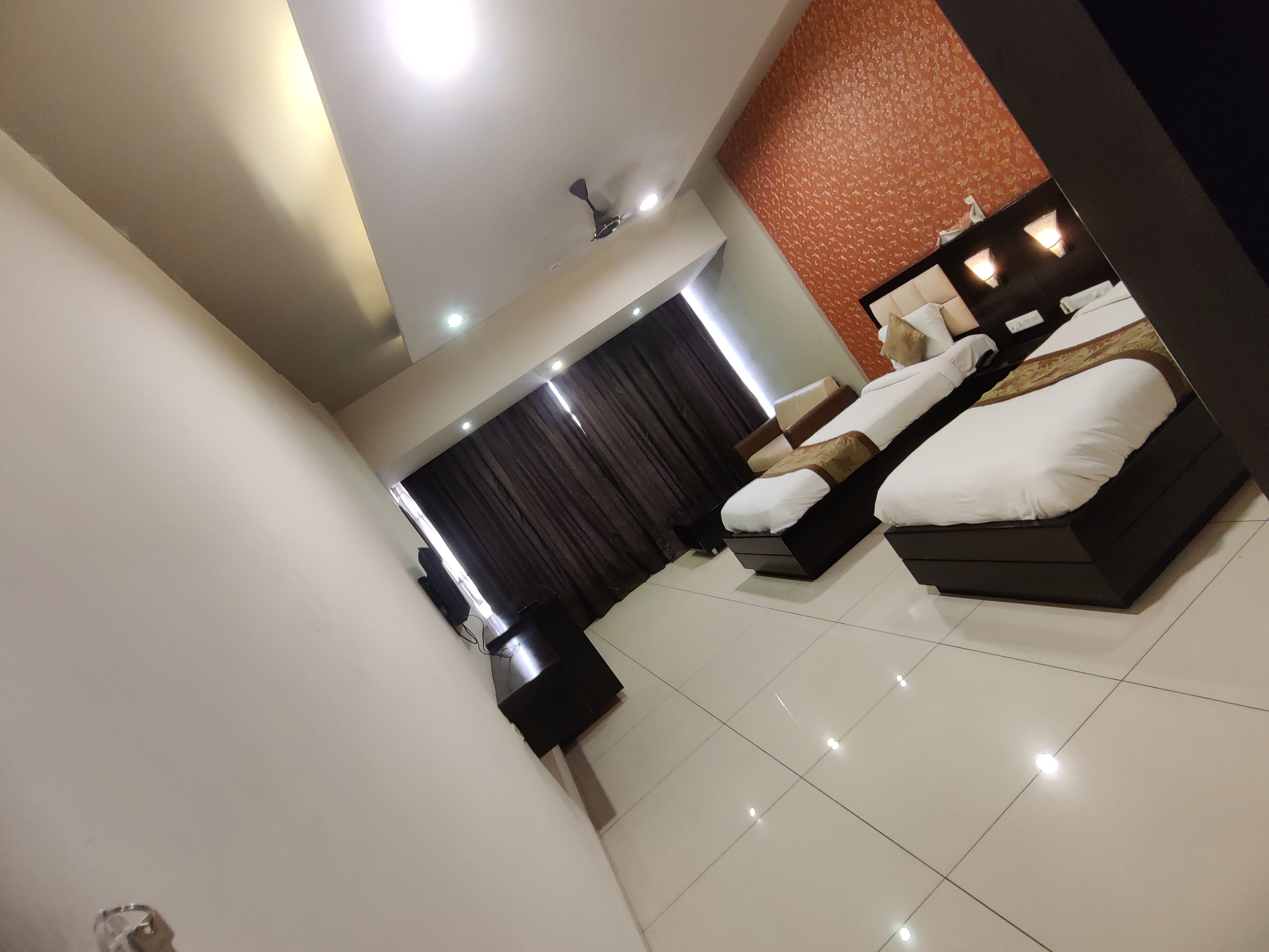 A modern hotel room with a large bed, a flat-screen TV, and a ceiling fan.