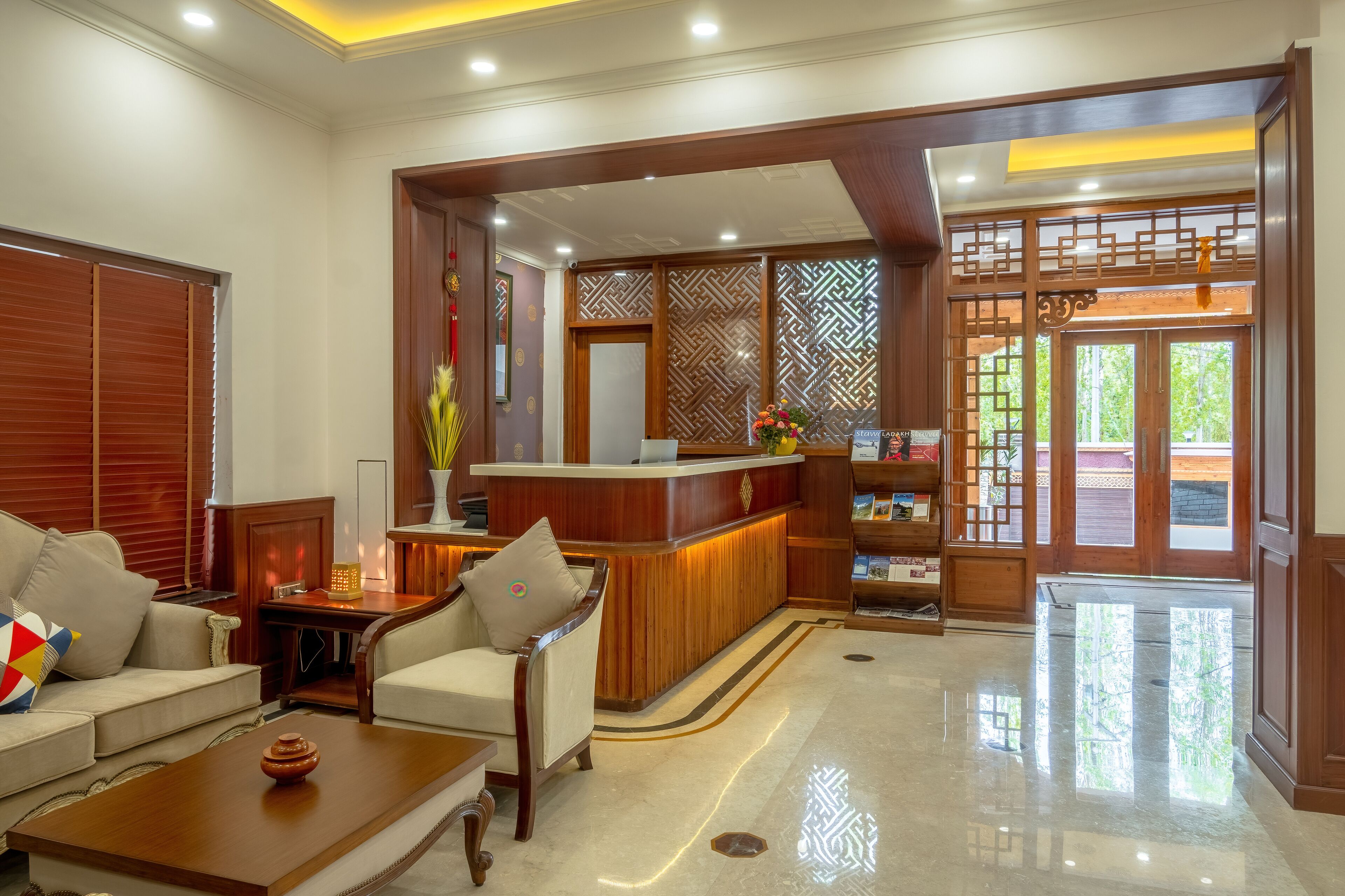 A hotel lobby with a reception desk, seating area, and a decorative wooden partition.