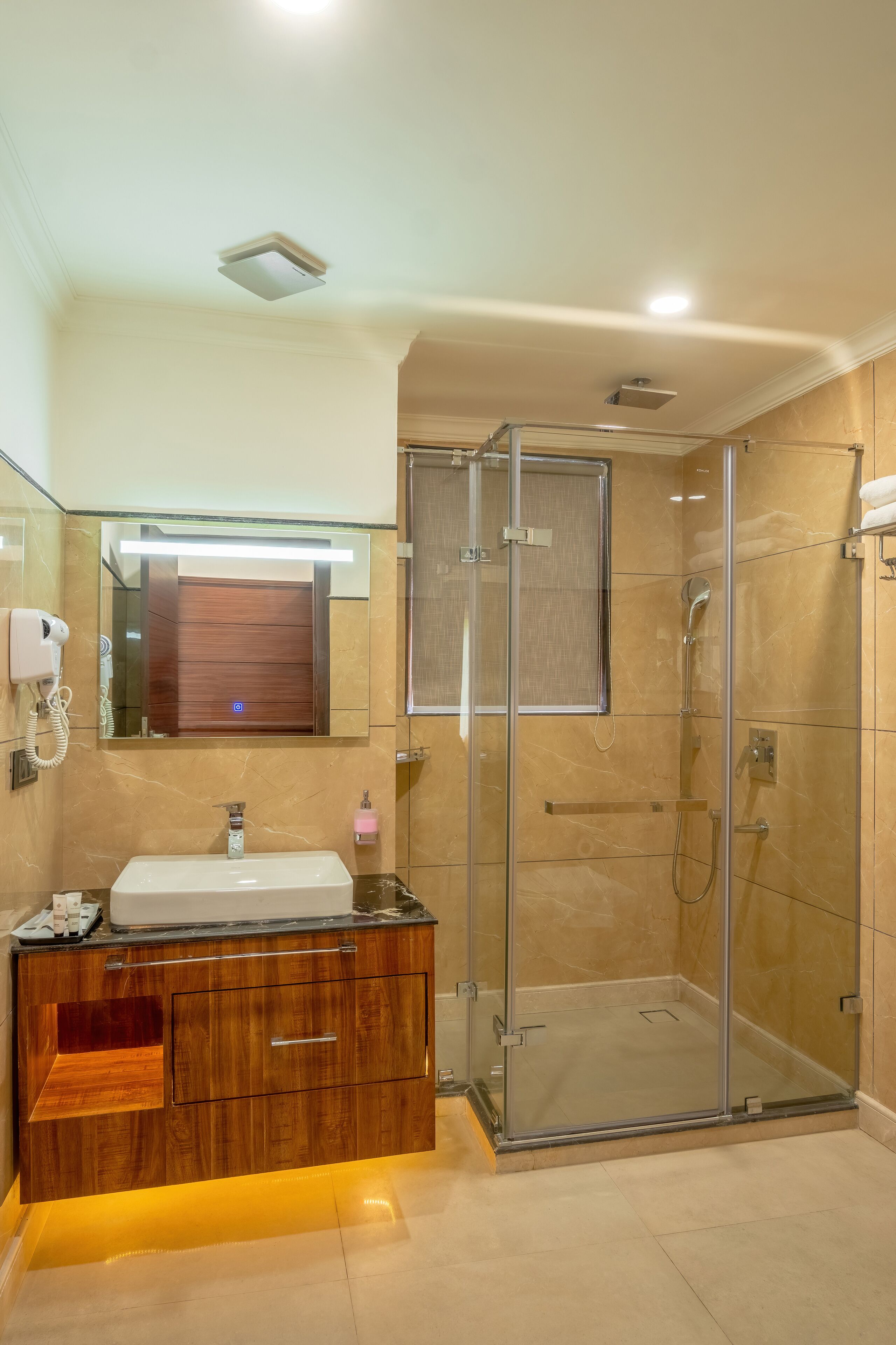 Une salle de bain moderne dotée d’une douche à parois de verre, d’un meuble-lavabo avec miroir et d’un sèche-cheveux intégré.