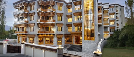 Een meerlaags gebouw met balkons, grote ramen en een goed verlichte ingang.
