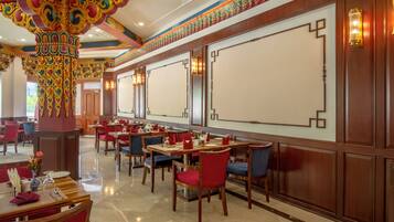 Un restaurante con mesas y sillas de madera, pilares decorativos e iluminación empotrada en las paredes.