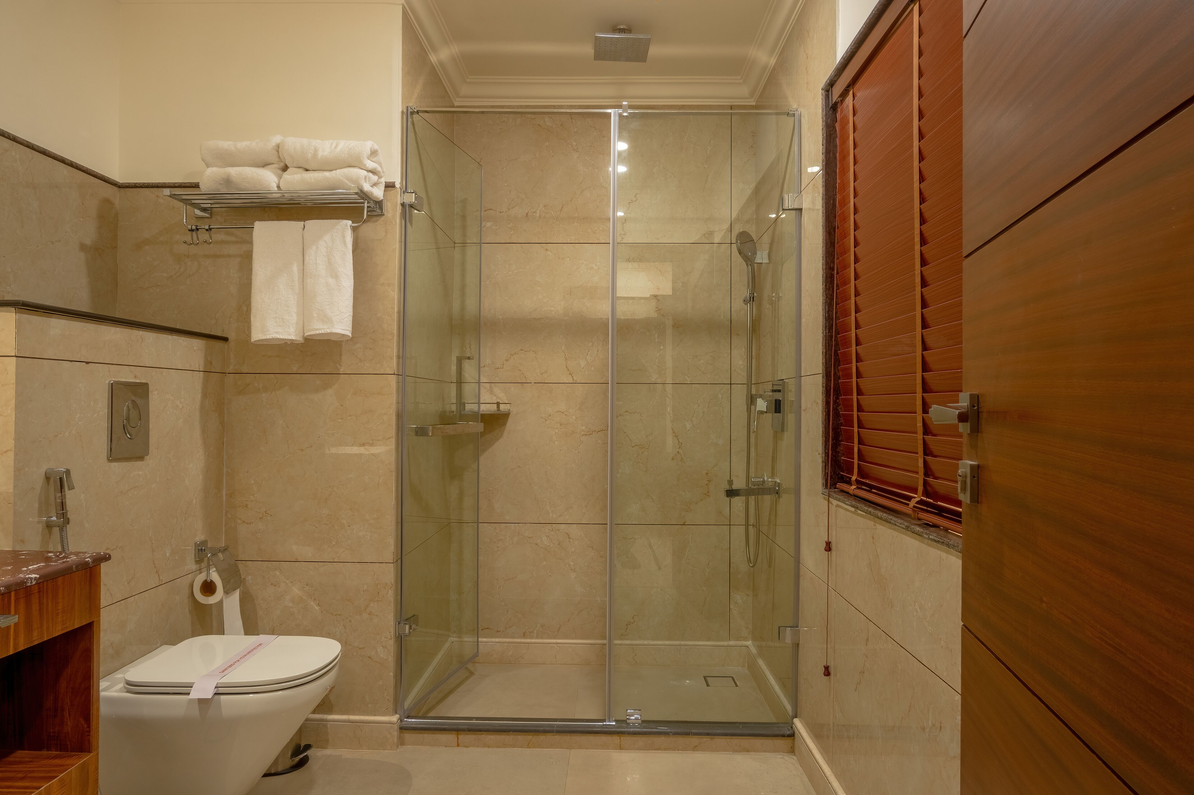 Een moderne badkamer met een douchecabine van glas, een toilet en een houten wastafelmeubel.