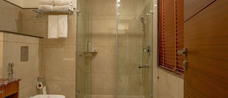 A modern bathroom with a glass-enclosed shower, a toilet, and a wooden vanity.