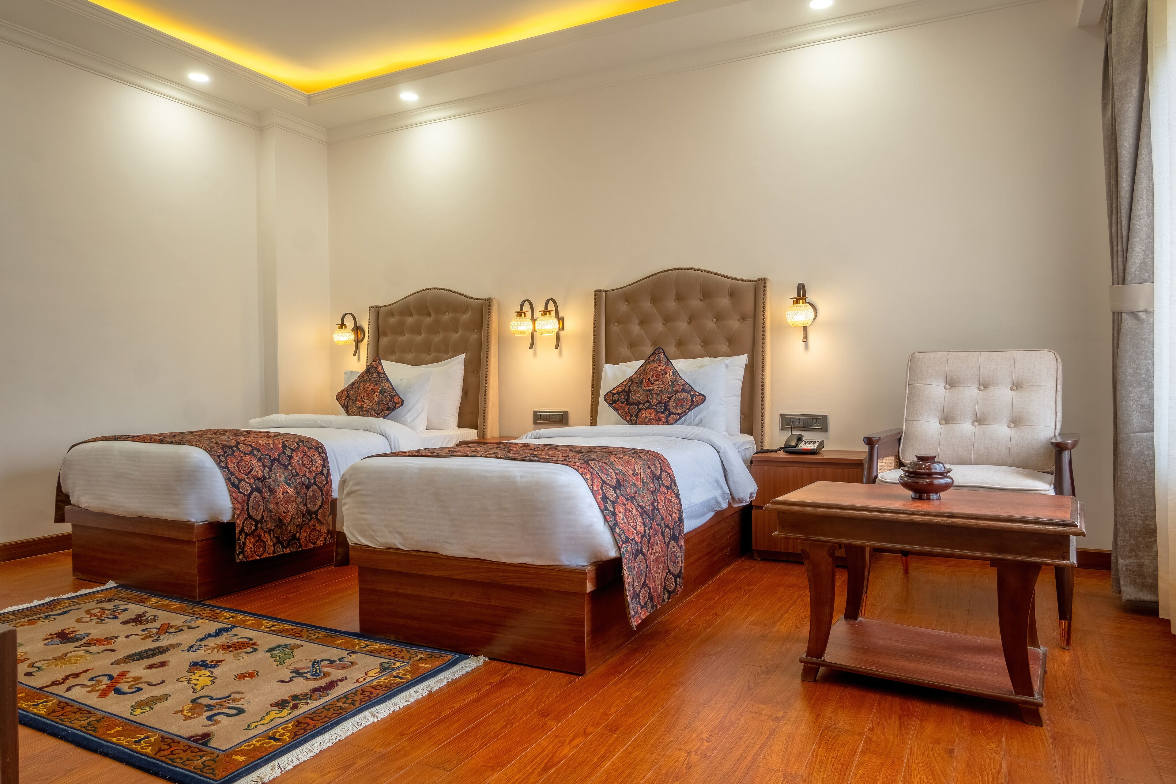 Ein Hotelzimmer mit zwei Betten, einer Sitzecke mit Tisch und einem dekorativen Teppich.
