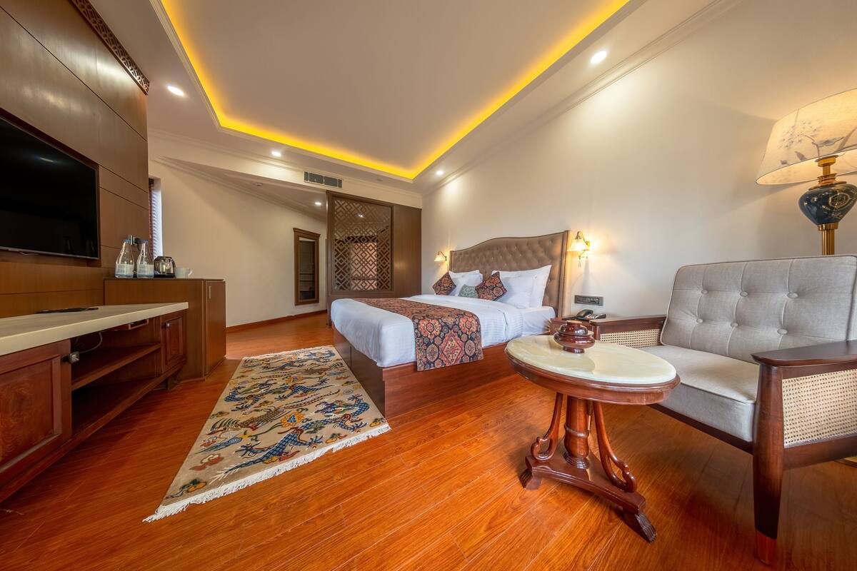 A hotel room with a bed, a sofa, a TV, and a wooden cabinet.