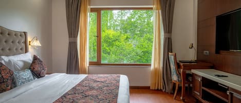 Een hotelkamer met een groot bed, een bureau, een televisie en een raam met gordijnen.