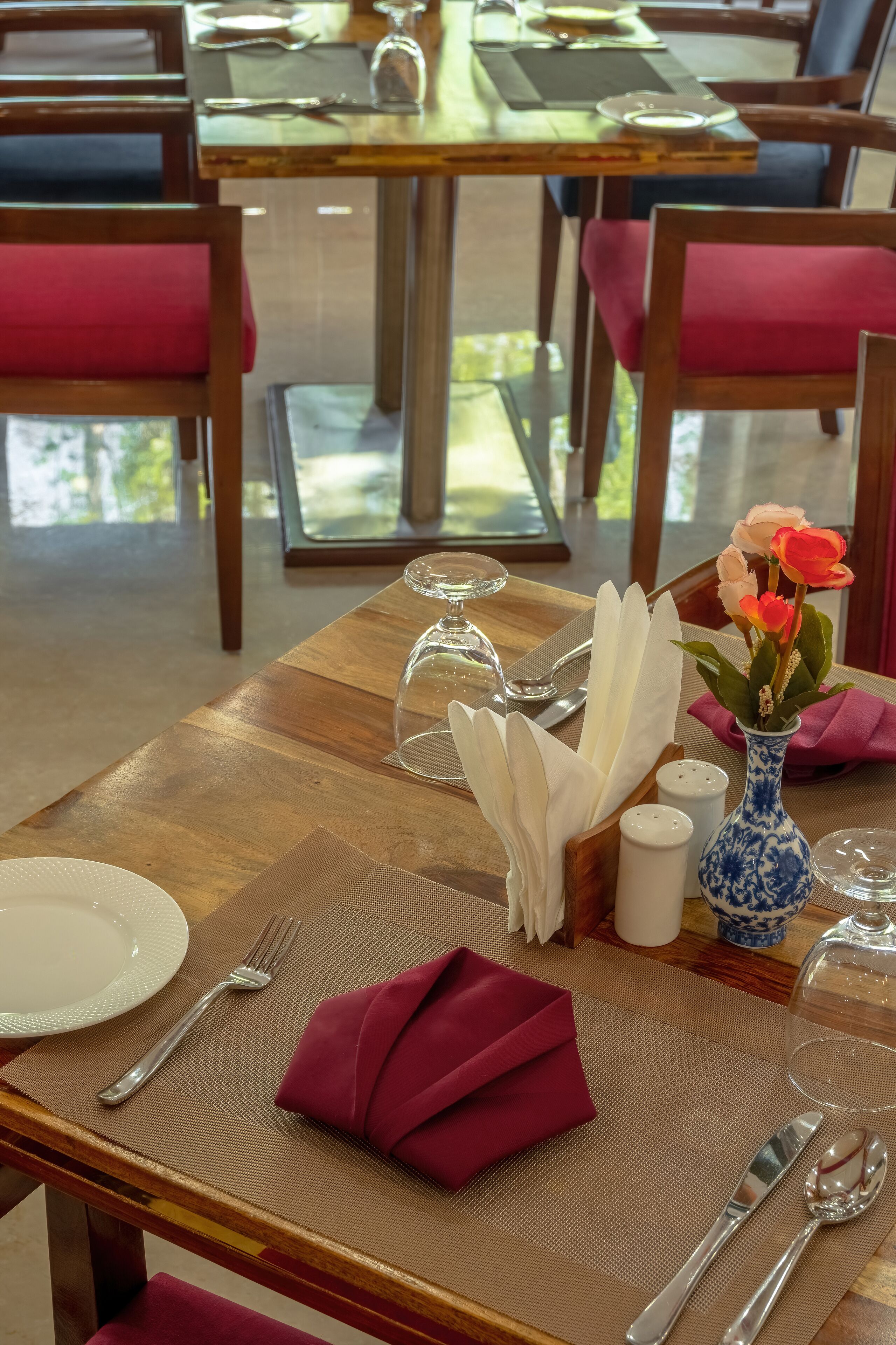 A dining table set with a folded napkin, a vase with flowers, salt and pepper shakers, and a glass dome.
