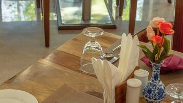 A dining table set with a folded napkin, a vase with flowers, salt and pepper shakers, and a glass dome.