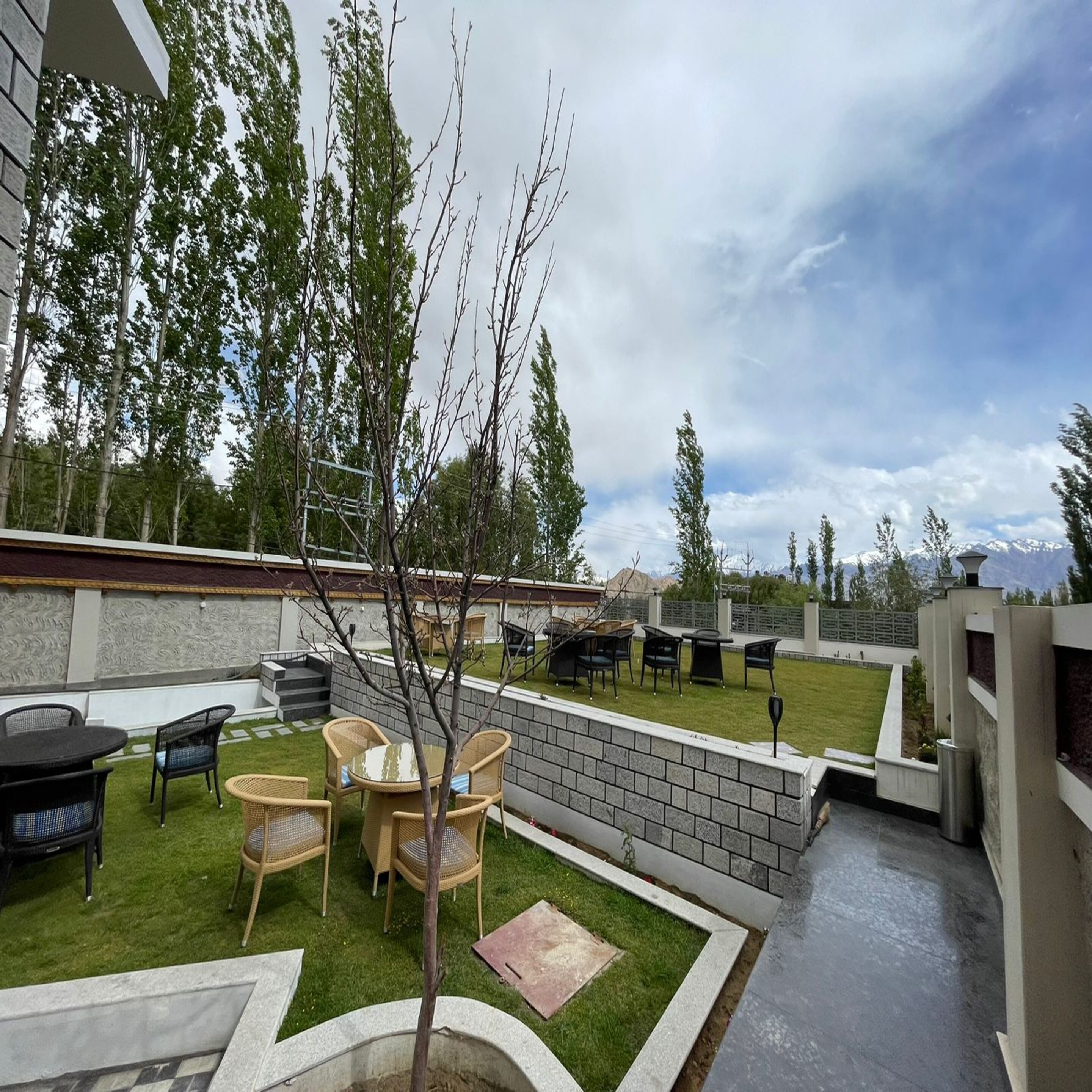 A patio area with outdoor furniture, a small tree, and a view of mountains in the background.