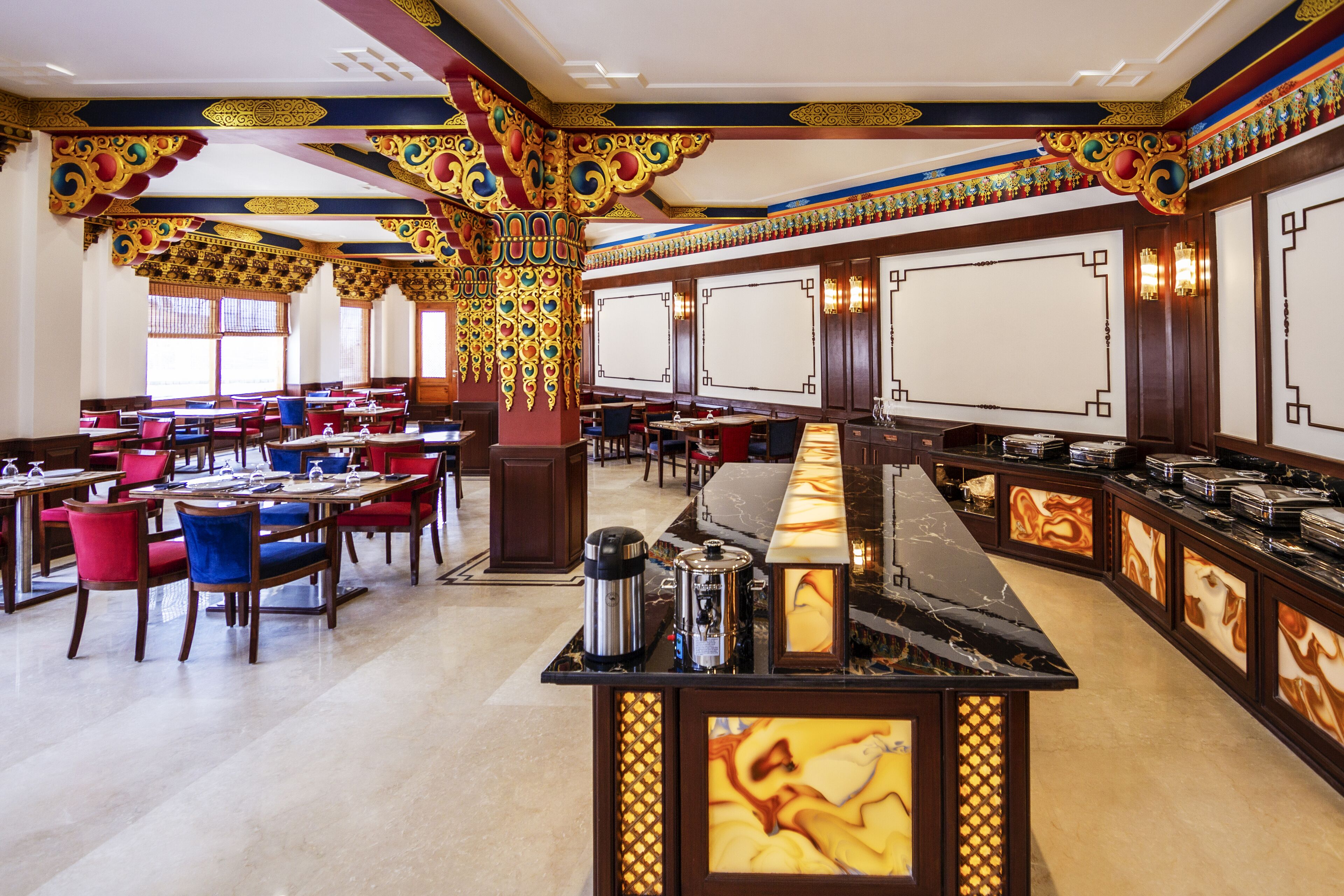 A restaurant with a long counter, multiple tables, and chairs.