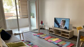 Olohuone, jossa on sohva, televisio, pieni pöytä ja värikäs matto.