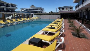 Ein Poolbereich mit Liegestühlen und blauem Himmel.