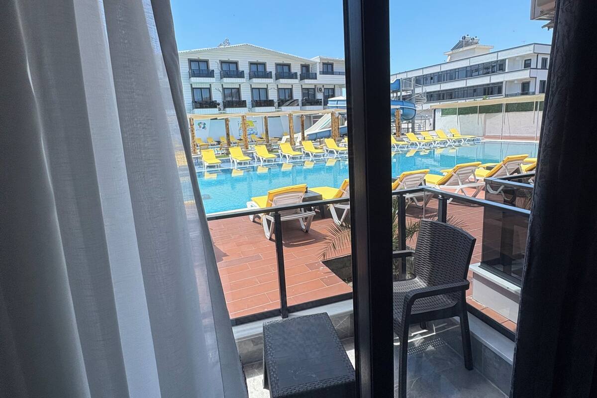 A balcony with a pool view, a chair, and a small table.