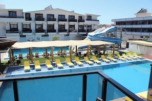 A rooftop pool with sun loungers and a covered area, surrounded by buildings.