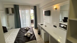 Ein Hotelzimmer mit Bett, Schreibtisch, Fernseher und Spiegel im Badezimmer.